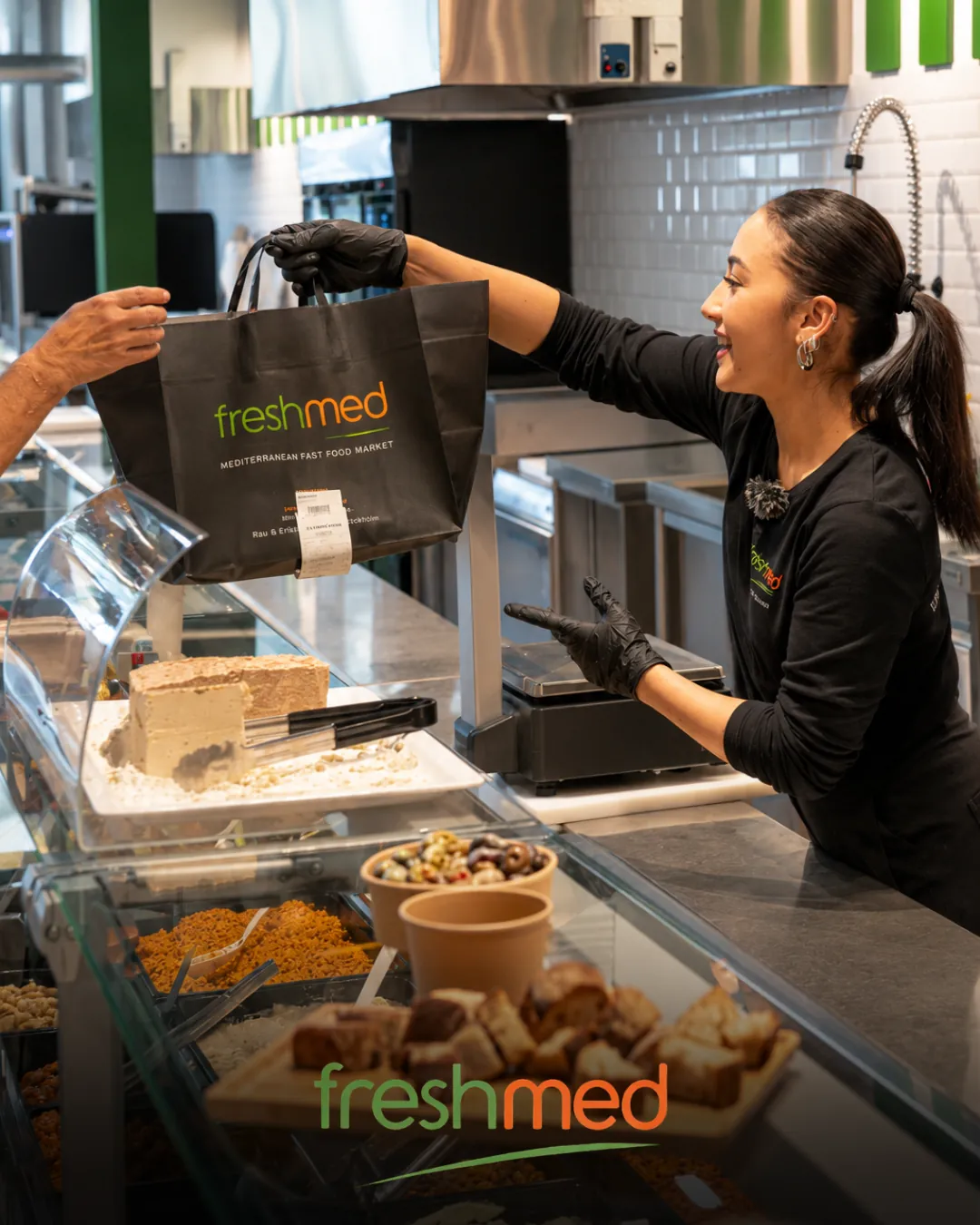 Freshmed : une vendeuse tend un sac au comptoir traiteur